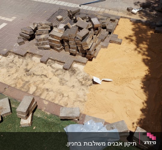 אבנים משתלבות, חול וכלי עבודה באתר שיפוץ